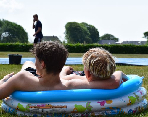 To efterskoledrenge sidder i et lille badebassin i haven på Sædding Efterskole 