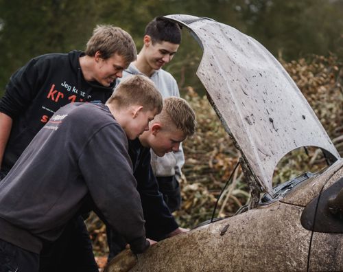 Efterskoleelever ser i motoren på en markræs bil