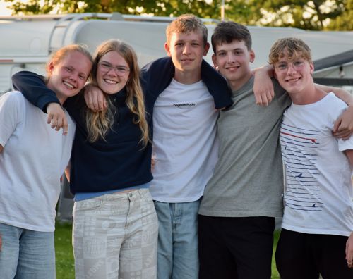 En flok glade efterskoleelever fra Sædding Efterskole, står med armene rundt om hinanden og smiler til kameraet.