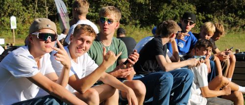 Drengene fra Sædding Efterskole nyder solen på en bænk på deres drengetur