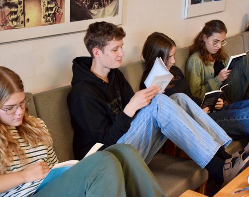 En flok efterskoleelever sidder i sofaerne på Sædding Efterskole og læser i bøger