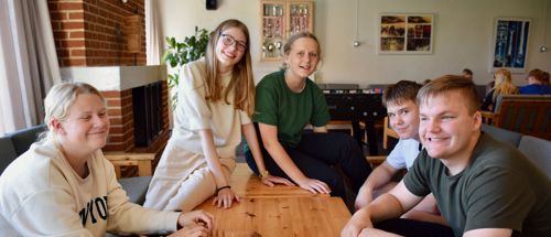 En flok elever i sofaerne omkring et bord i dagligstuen på Sædding Efterskole 