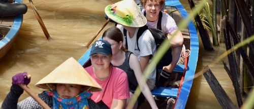 Elever fra Sædding Efterskole er ude at sejle på en flod med. En vietnamesisk kvinde ror. 