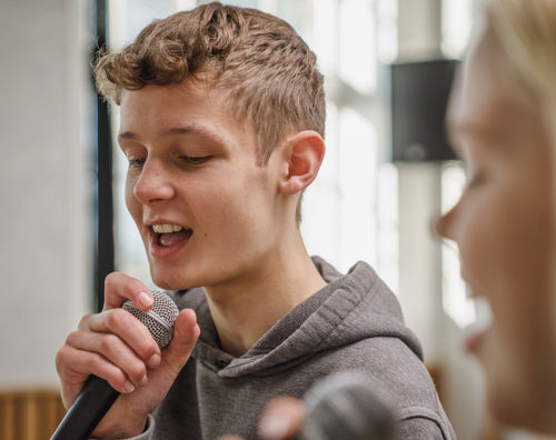 Efterskoleelev synger i mikrofon til musik på Sædding Efterskole