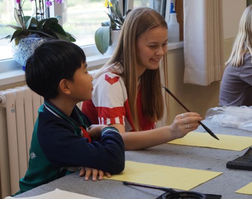 En elev fra Sædding Efterskole lærer at tegne kinesiske tegn af en skoleelev i Kina