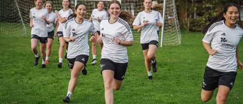 Sædding Efterskoles pigehold laver opvarmning på fodboldbanen