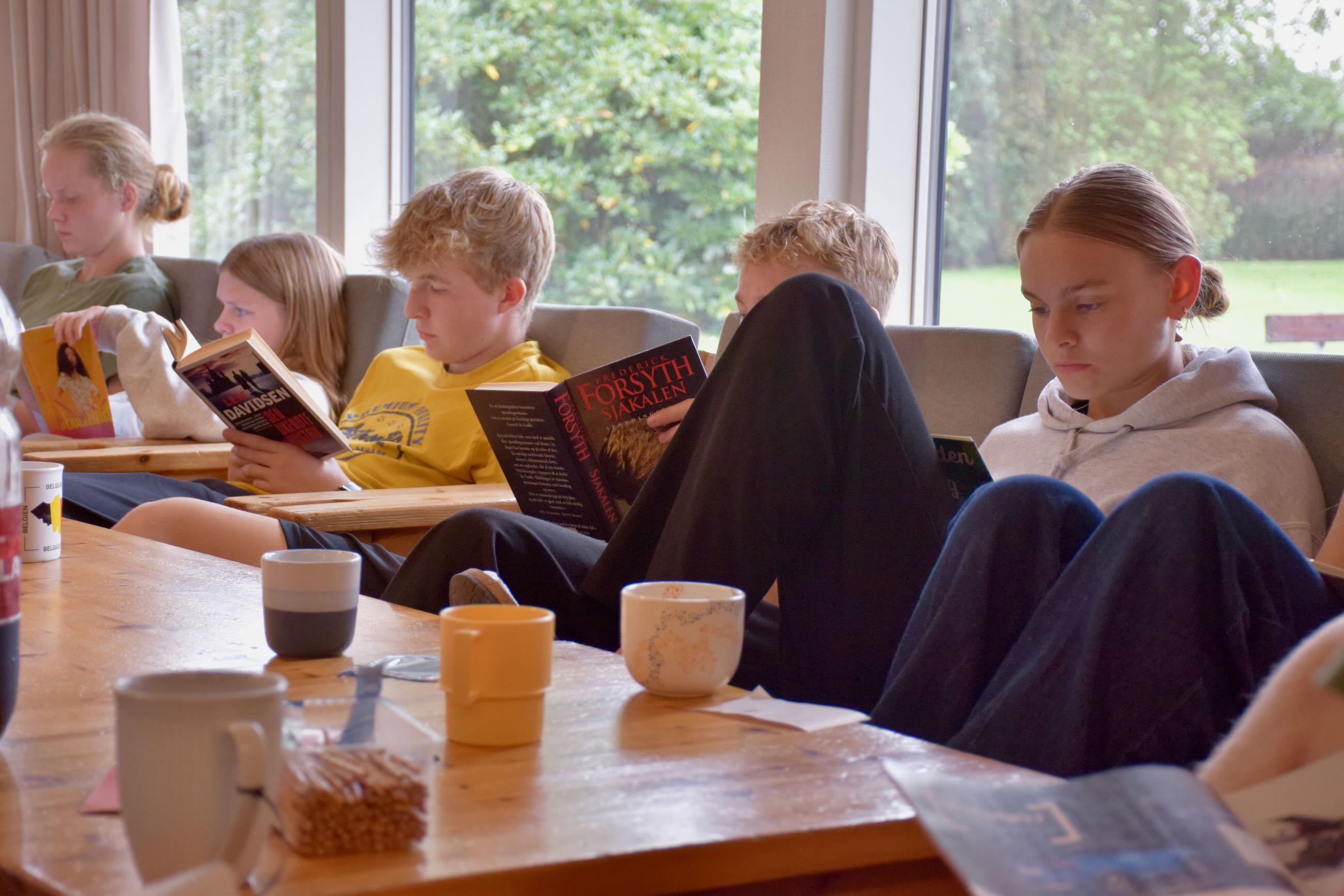 Undervisning på efterskole. Efterskoleelever sidder i dagligstue på Sædding Efterskole og læser i bøger. 