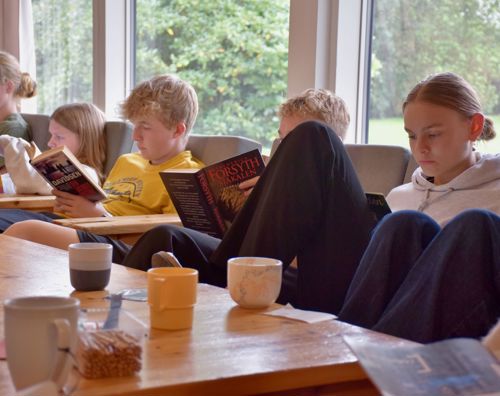 Efterskoleelever sidder i dagligstue på Sædding Efterskole og læser i bøger. 