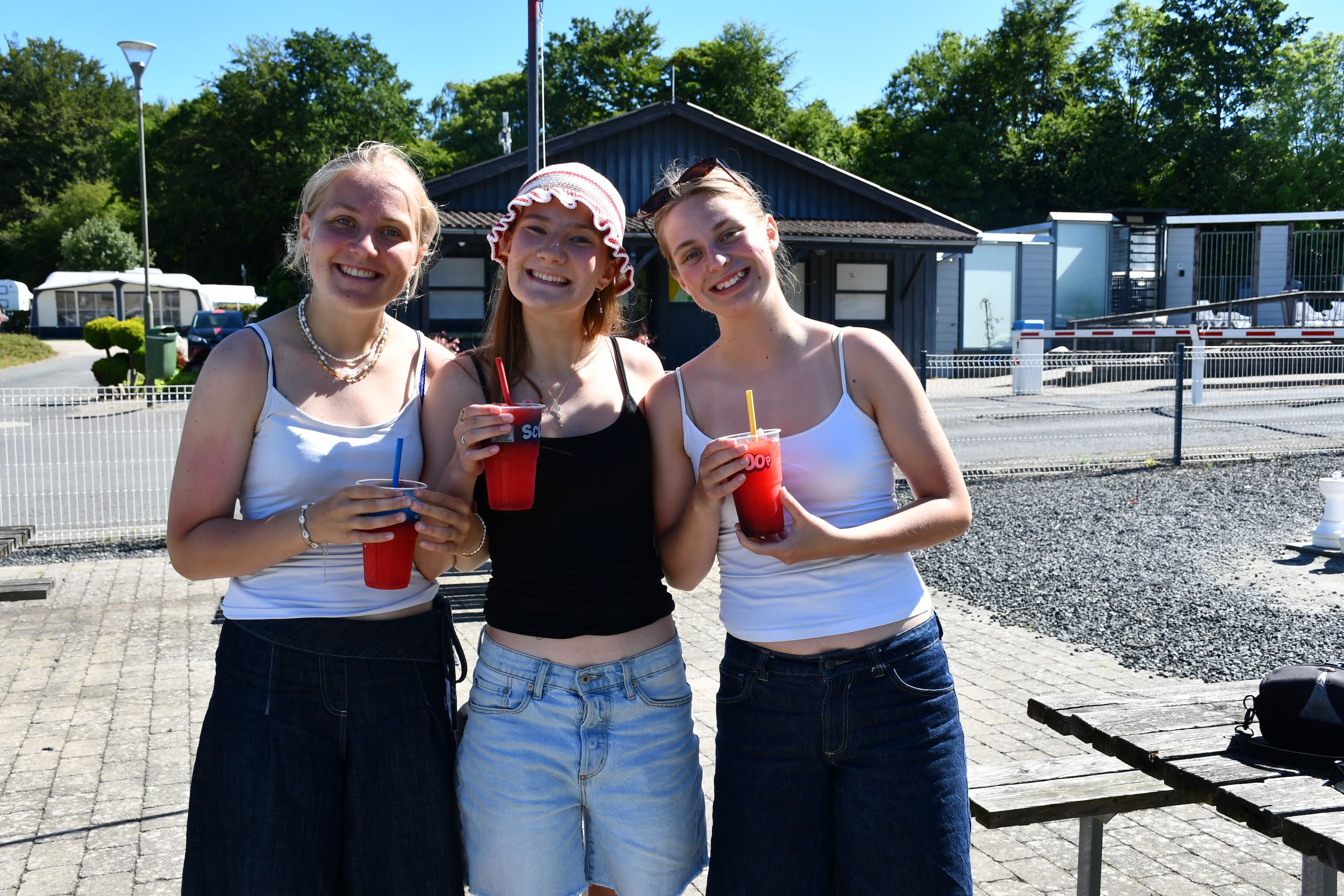 Afslutningstur med Sædding Efterskole på Mørkholt Camping | Tre efterskolepiger står med Sluch ice og smiler. 