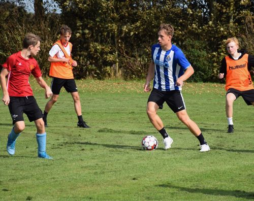 Drenge fra Sædding Efterskole spiller fodbold. En dreng dribler med bolden