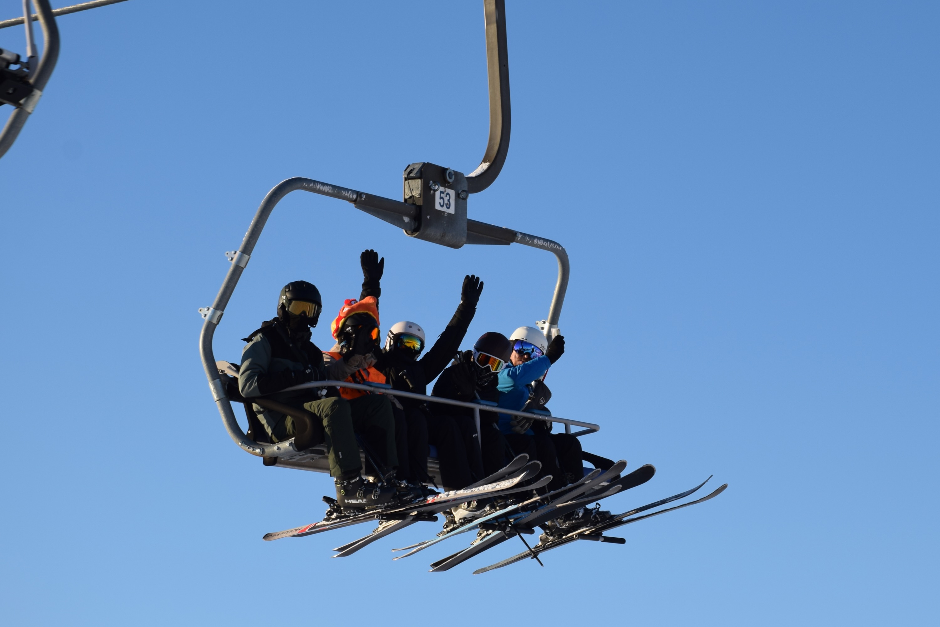 Fem elever sidder i en lift med ski på - højt oppe og vinker ned til de andre fra Sædding Efterskole