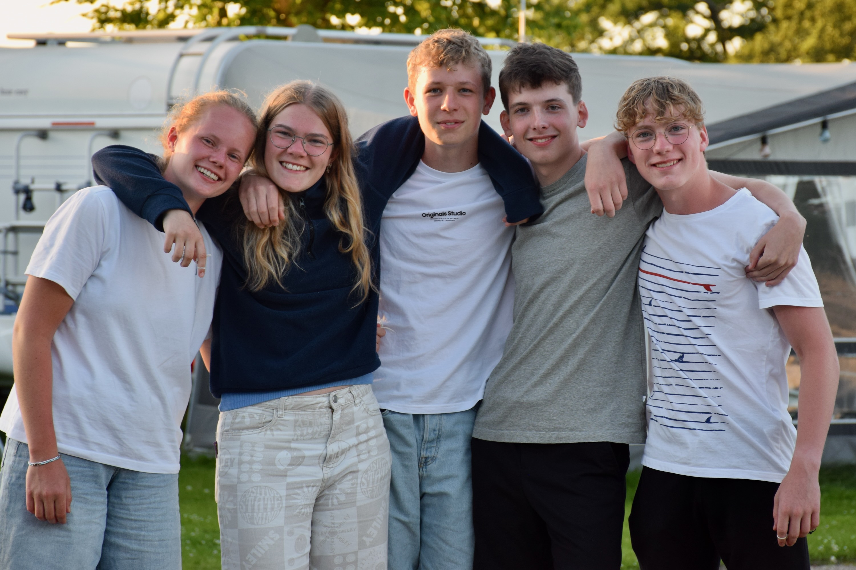 En flok glade efterskoleelever fra Sædding Efterskole, står med armene rundt om hinanden og smiler til kameraet.