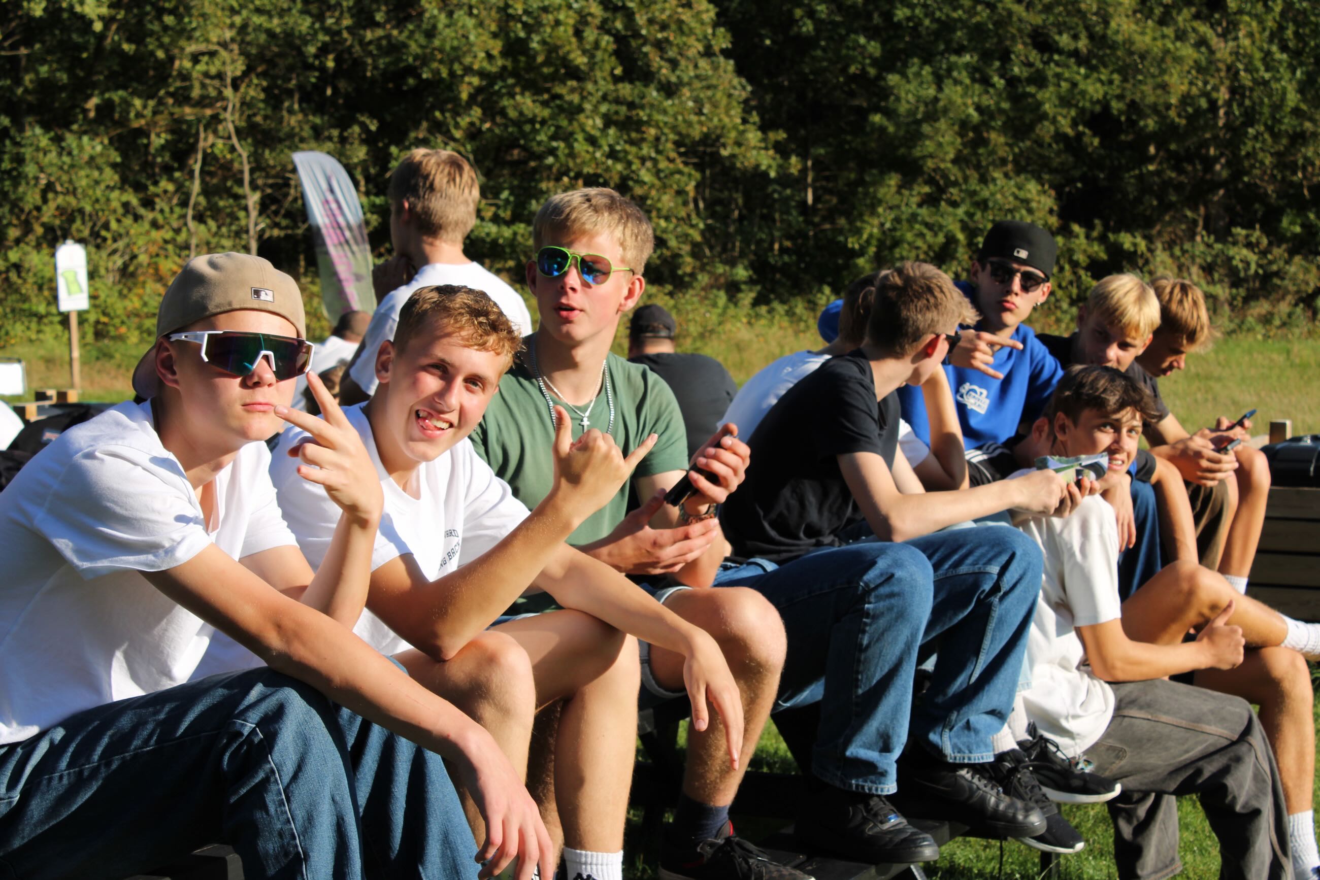 Drengene fra Sædding Efterskole nyder solen på en bænk på deres drengetur