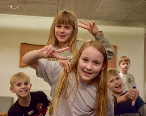 Glade børn smiler og laver V tegn med fingrene på Sædding Efterskole til årets Funpark
