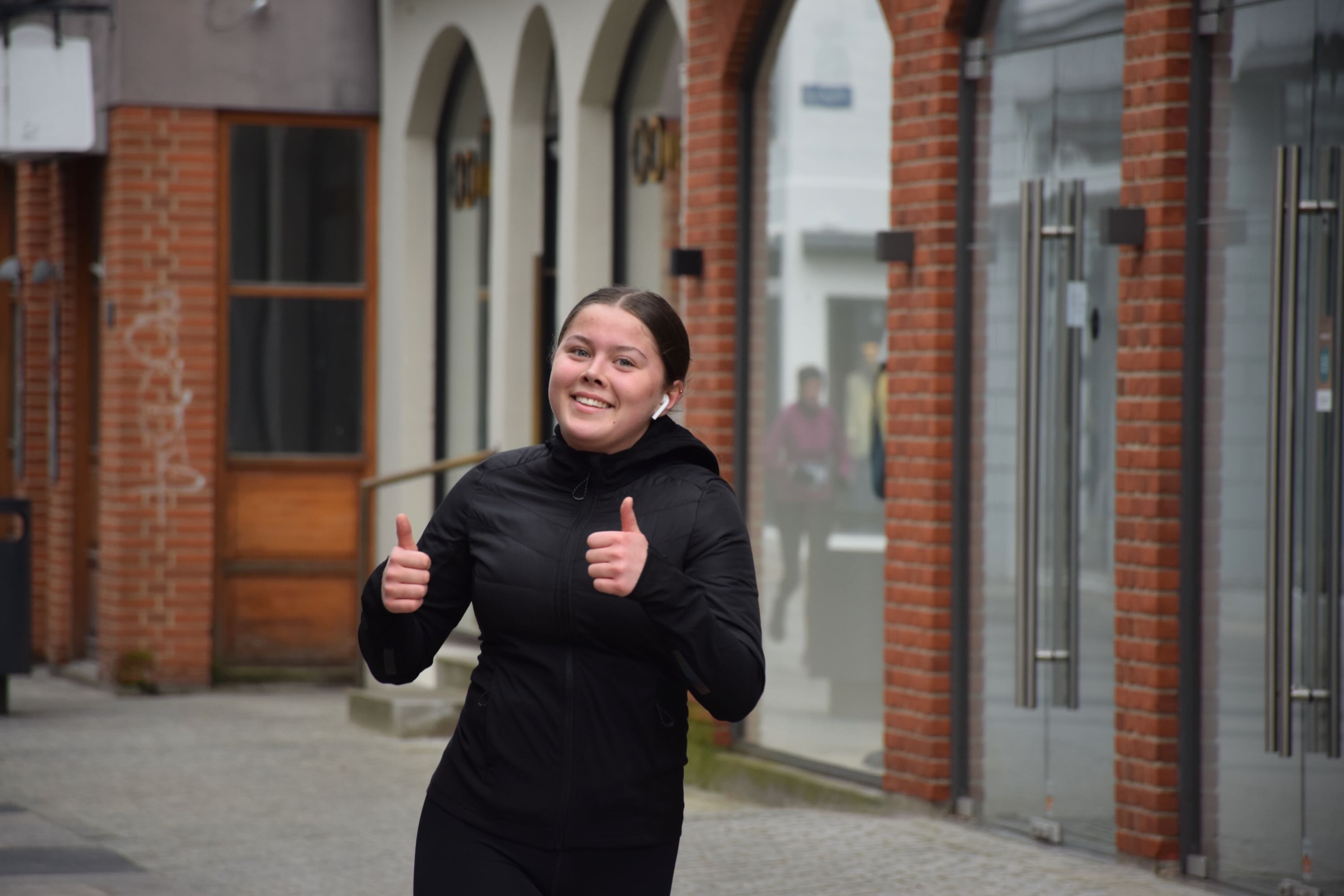 Efterskolepige viser tumps up mens hun løber halvmarathon i Holstebro med Sædding Efterskole