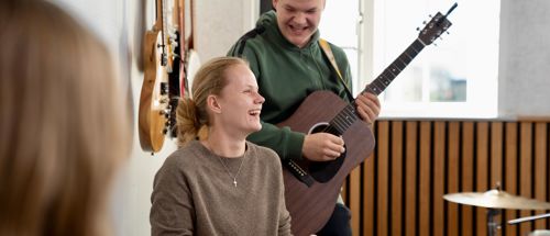 To elever spiller i musiklokalet på Sædding Efterskole på henholdsvis klaver og guitar