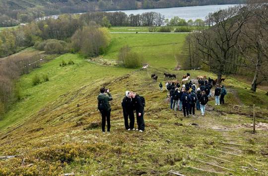 En flok elever går ned ad en bakke. Der er vand i baggrunden. Sædding Efterskole er på vandretur på hærvejen.