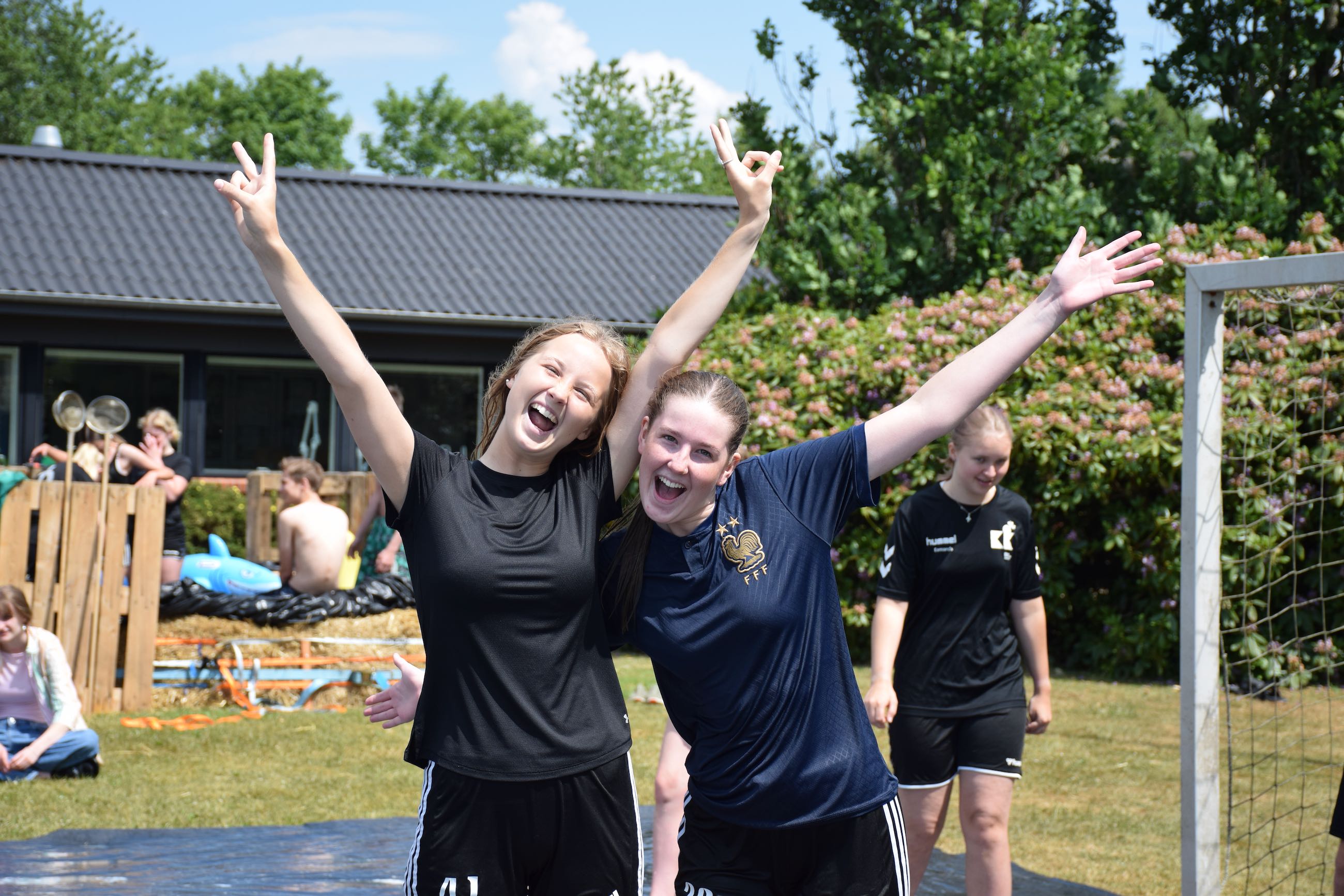 Hverdag Sædding Efterskole | To piger efterskolepiger spreder begejstret armene i vejret i Sædding Efterskoles have