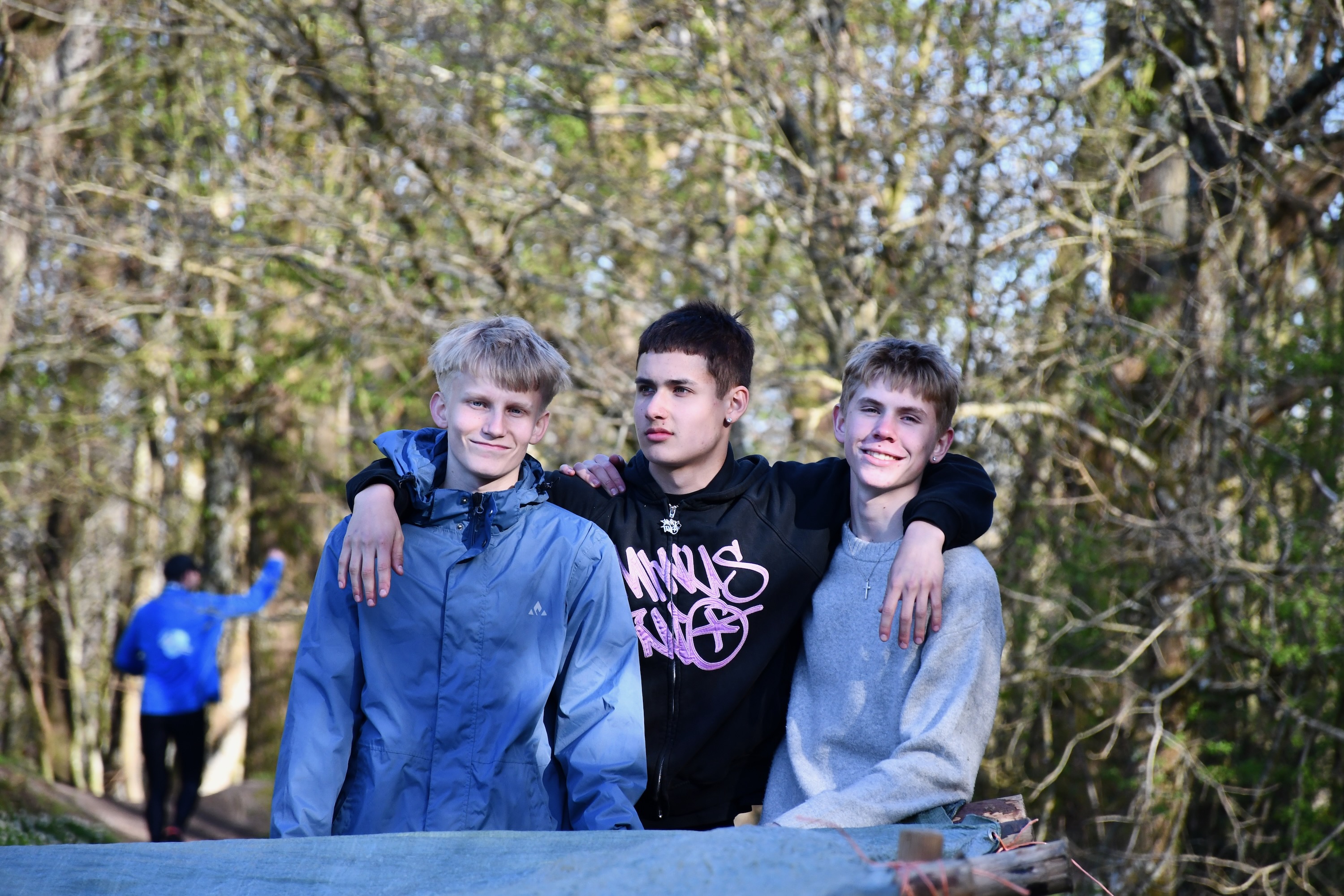 Tre drenge fra Sædding Efterskole smiler til kameraet, mens de er i gang med at lave en bivauk, som de skal sove i på årets hærvejstur. 