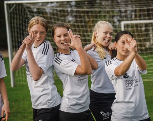 4 piger står i Sædding Efterskoles sportstøj på boldbanen og er klar til at spille fodbold.