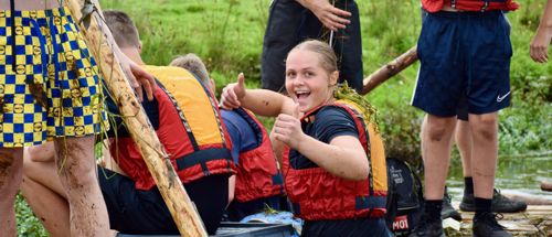 Efterskolepige giver thumbs up på tømmerflåde