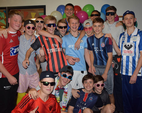 Efterårets temafest på Sædding Efterskole var børnefødselsdag. Her ses en flok drenge foran billedvæggen.