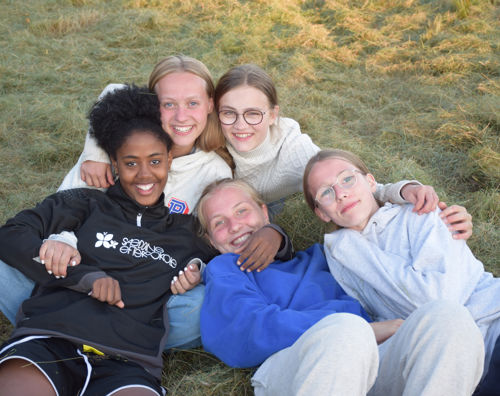 Viceleder søges til Sædding Efterskole. Her ses fem piger fra Sædding Efterskole, som ligger sammen i græsset og smiler til kameraet.