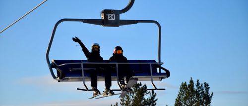 To efterskoleelever fra Sædding Efterskole sidder i en skilift og vinker. 