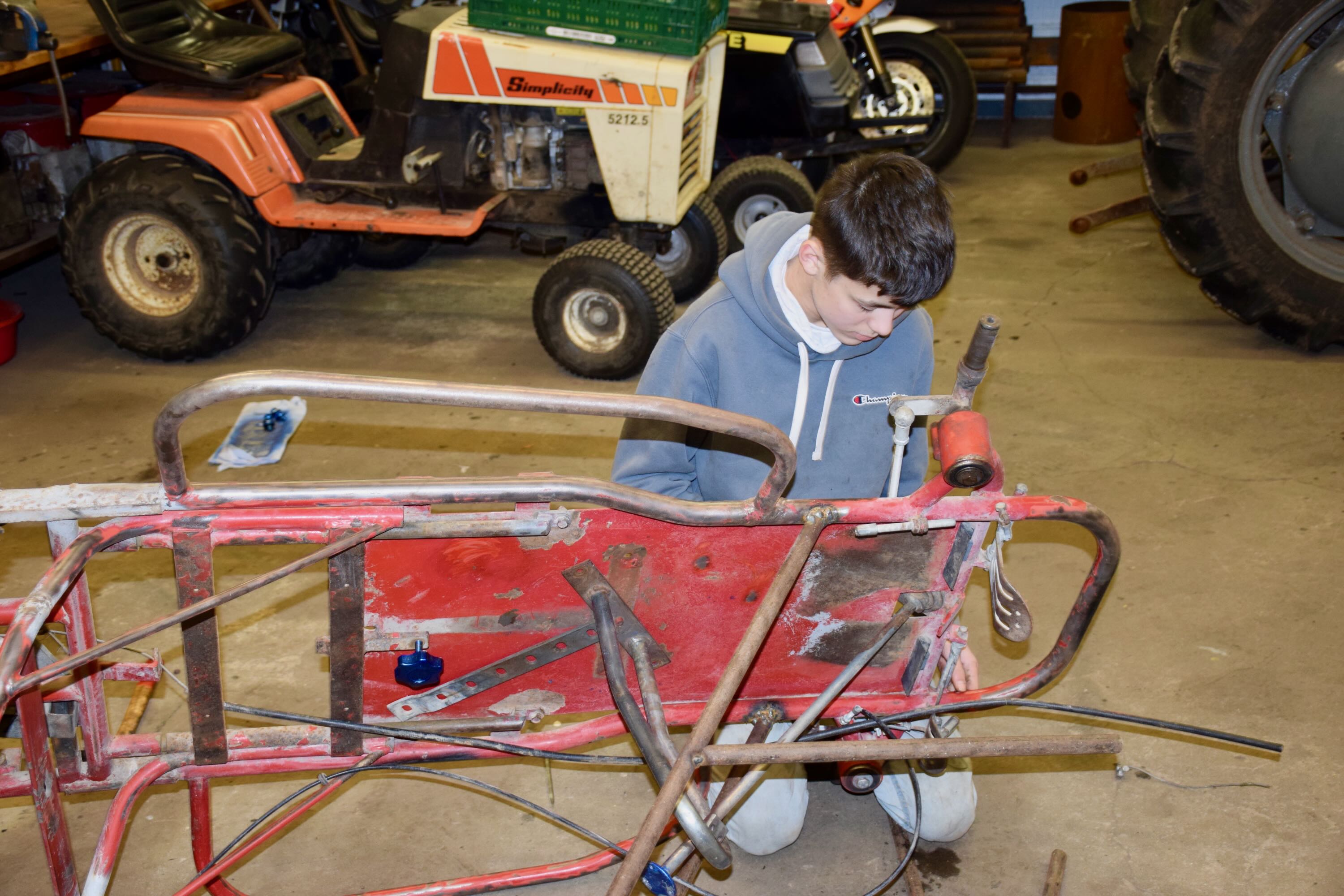 Motor værksted Sædding Efterskole | Efterskoledreng sidder på gulvet i værkstedet på Sædding Efterskole og er ved at reparere et køretøj.
