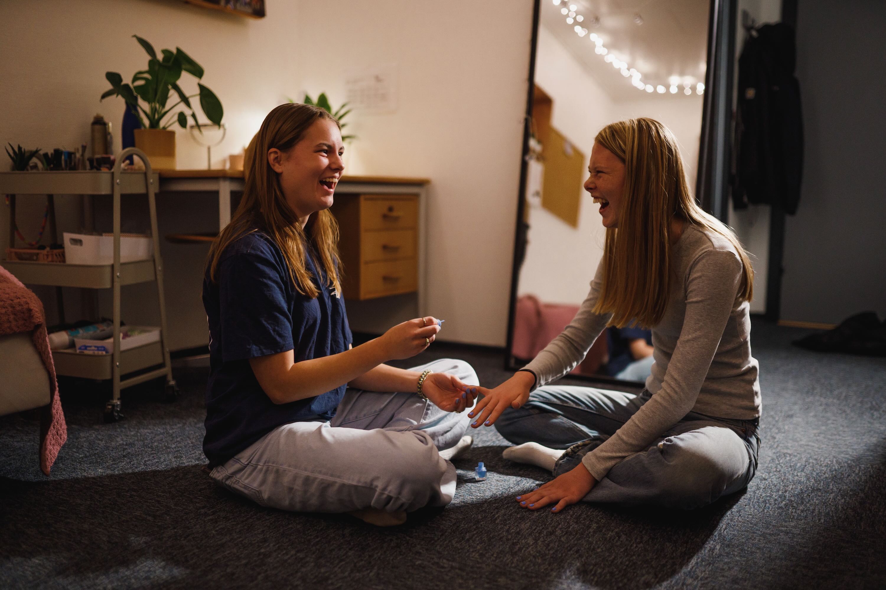 To efterskolepiger sidder på gulvet på værelset og hygger sig med at lægge neglelak