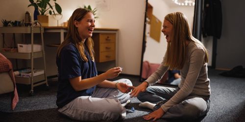 To efterskolepiger sidder på gulvet på værelset og hygger sig med at lægge neglelak